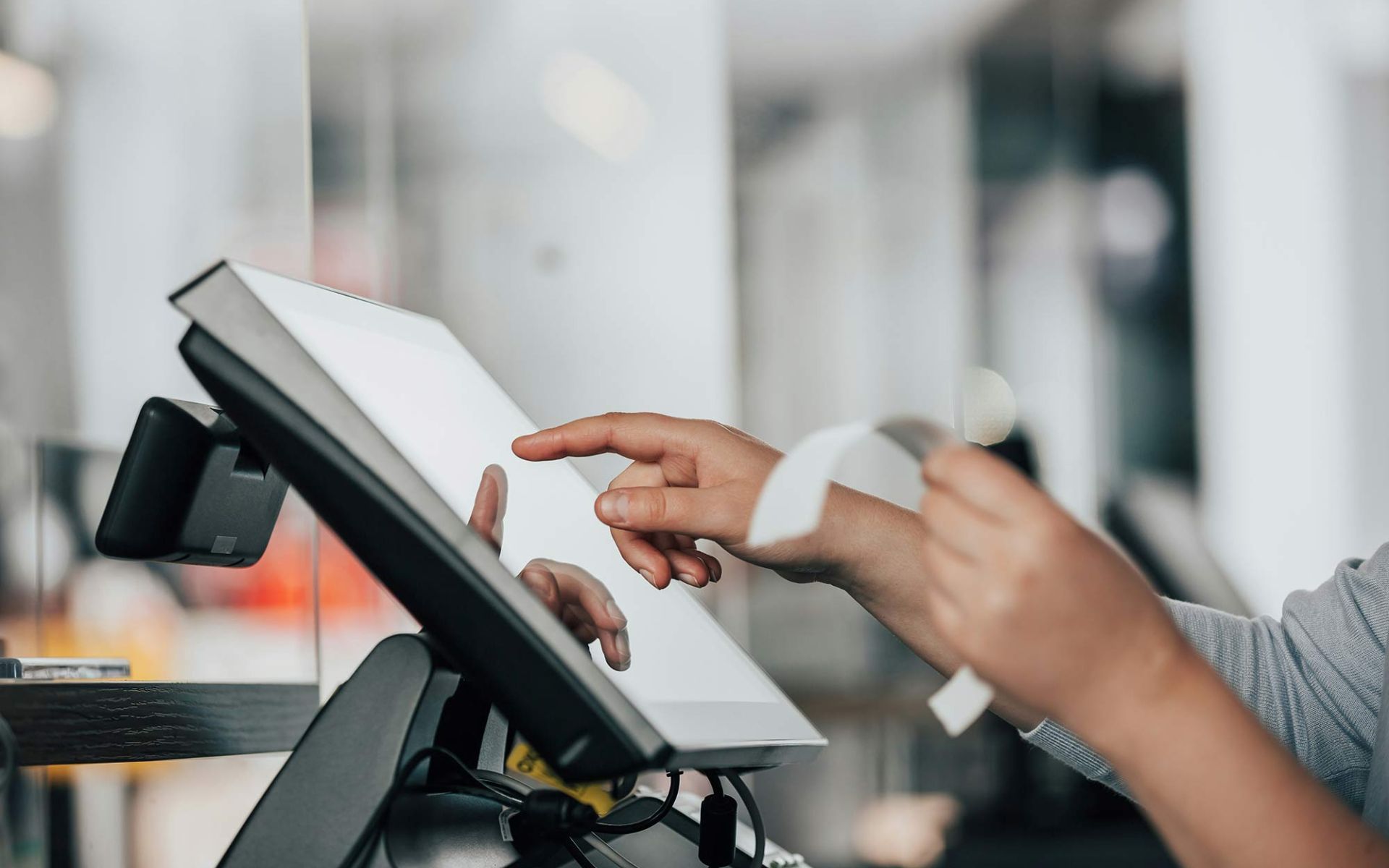 A hand processing a receipt on a POS machine