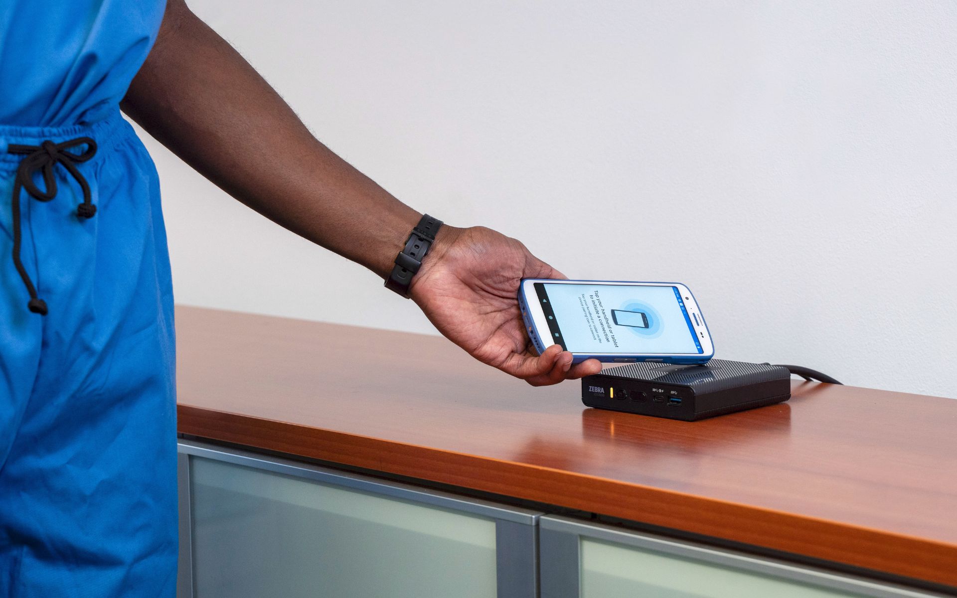 A hand holding a phone to a router