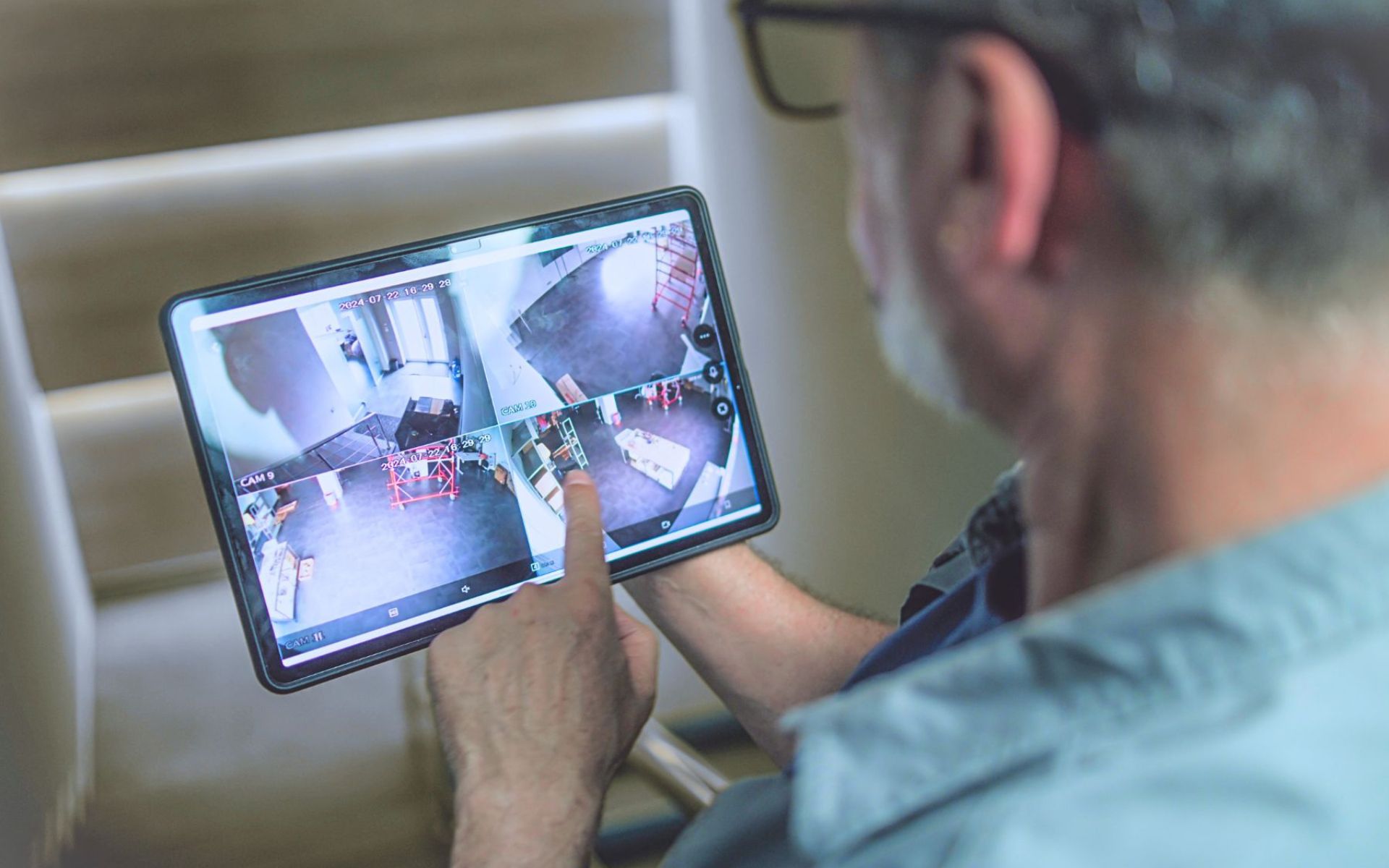 A man monitoring multiple points of his warehouse on one tablet screen