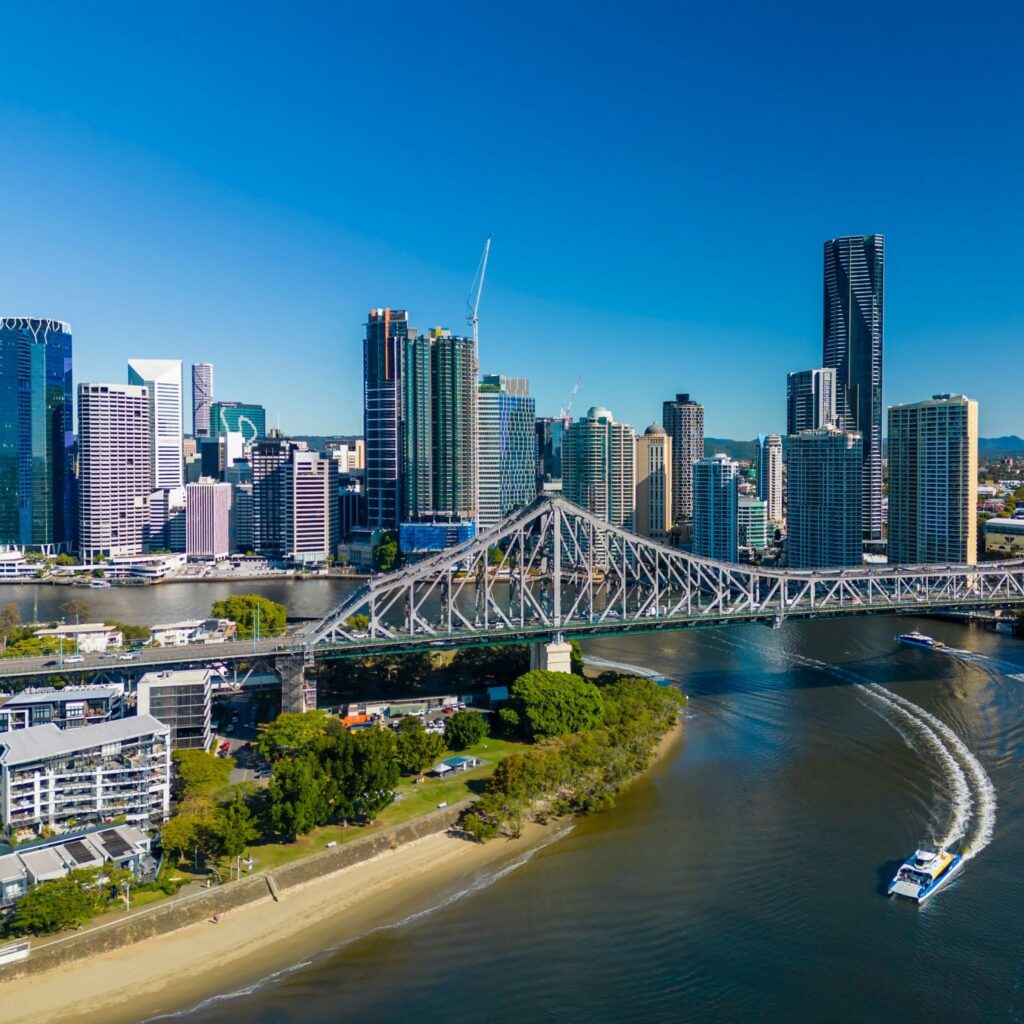 A wide shot of Brisbane River, with the story bridge and two ferries passing each other, with buildings in the background.