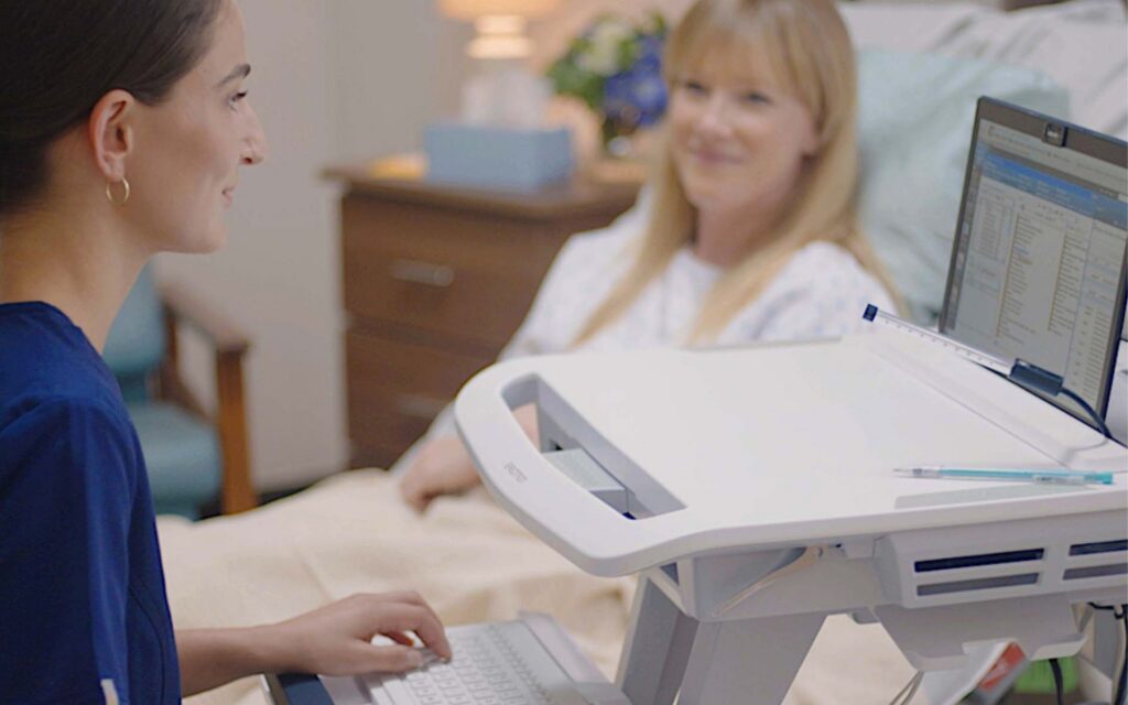 A nurse using an Ergotron medical cart while attending a patient